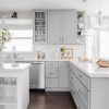 Light Grey kitchen cabinets with glass-front upper cabinets and a farmhouse sink