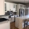Millennium White kitchen with a quartz waterfall island and glass-front wall cabinets