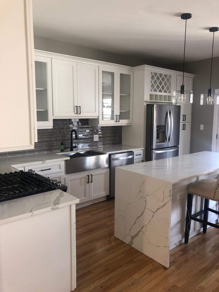 Millennium White kitchen with a quartz waterfall island and glass-front wall cabinets