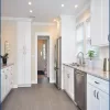 Millennium Off White kitchen cabinets in a galley layout with stainless appliances