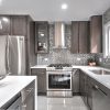 Dark Grey kitchen cabinets with a stainless range hood, refrigerator panel and mosaic backsplash
