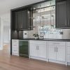 Millennium Grey kitchen cabinets with a beverage bar, glass shelving and mosaic tile backsplash