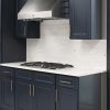 Millennium Blue kitchen cabinets with brass hardware, marble backsplash and a stainless hood