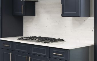 Millennium Blue kitchen cabinets with brass hardware, marble backsplash and a stainless hood