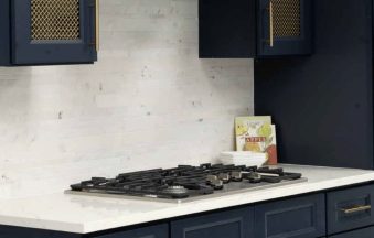 Millennium Blue kitchen cabinets with a gold mesh cabinet insert and marble countertop