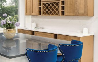 Cappuccino kitchen cabinets with a wine rack, grey island and blue velvet bar stools