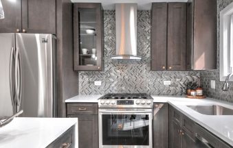 Dark Grey kitchen cabinets with a stainless range hood, refrigerator panel and mosaic backsplash