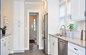 Millennium Off White kitchen cabinets in a galley layout with stainless appliances