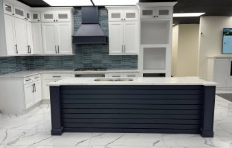 Millennium Blue kitchen island with white perimeter cabinets and a stainless range hood